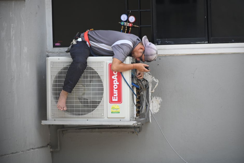 Técnico HVAC instalando una unidad de aire acondicionado residencial